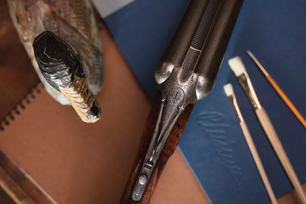 gun next to wooden duck and paint brushes