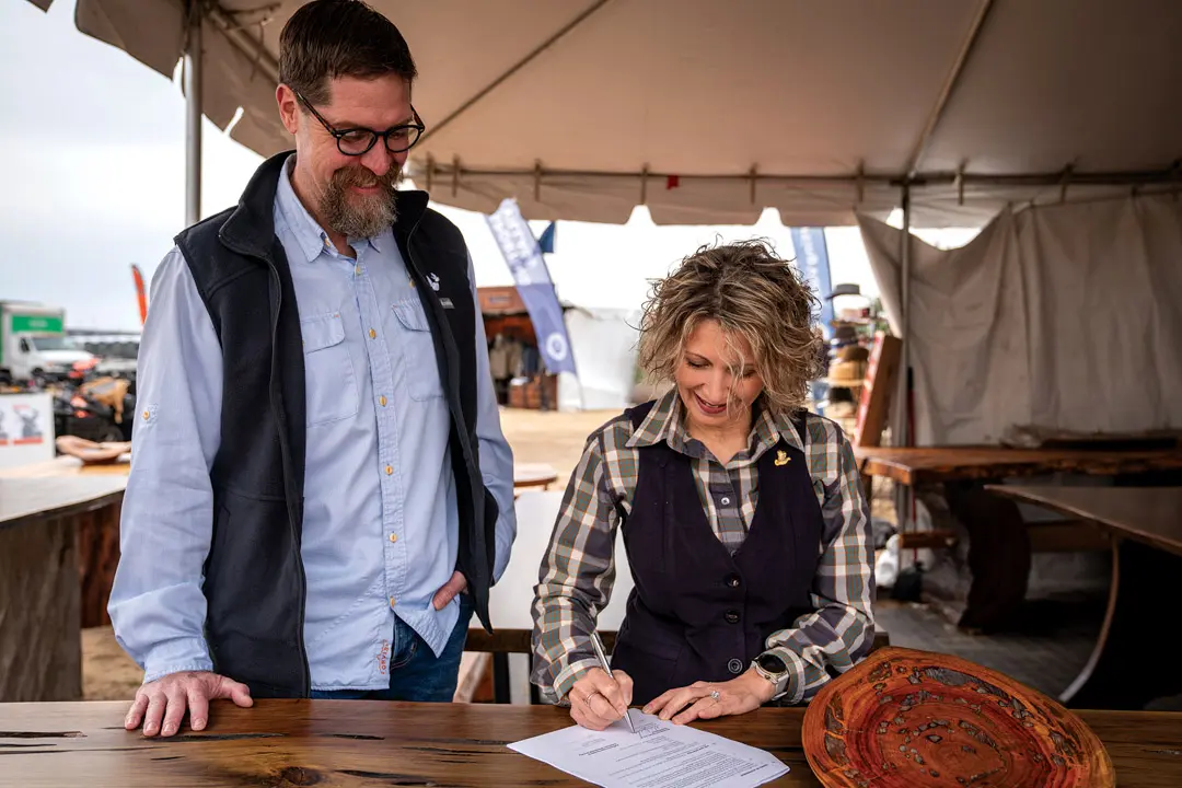 two people smiling while signing a document