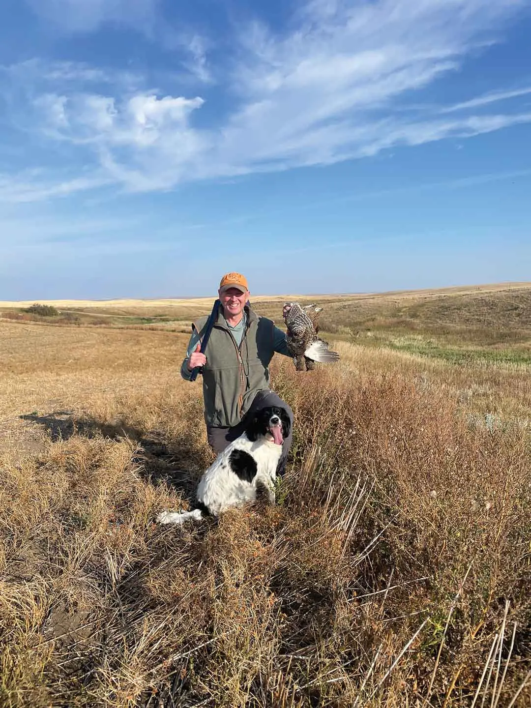 Man with dog posing holding a felled bird
