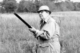black and white photo of a man with a gun in a field