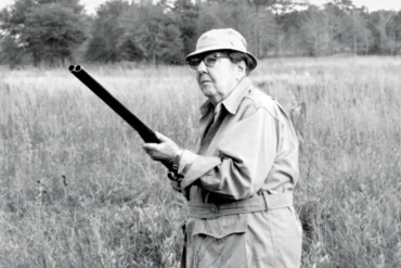 black and white photo of a man with a gun in a field