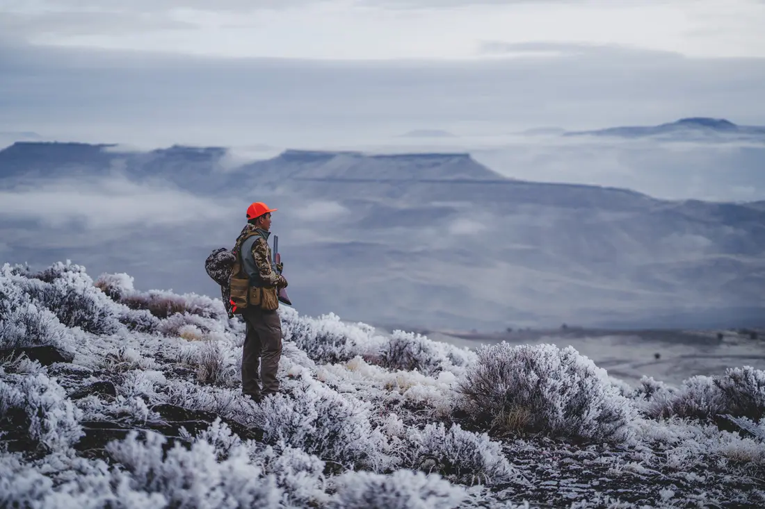 man staring out over the horizon with hunting gear