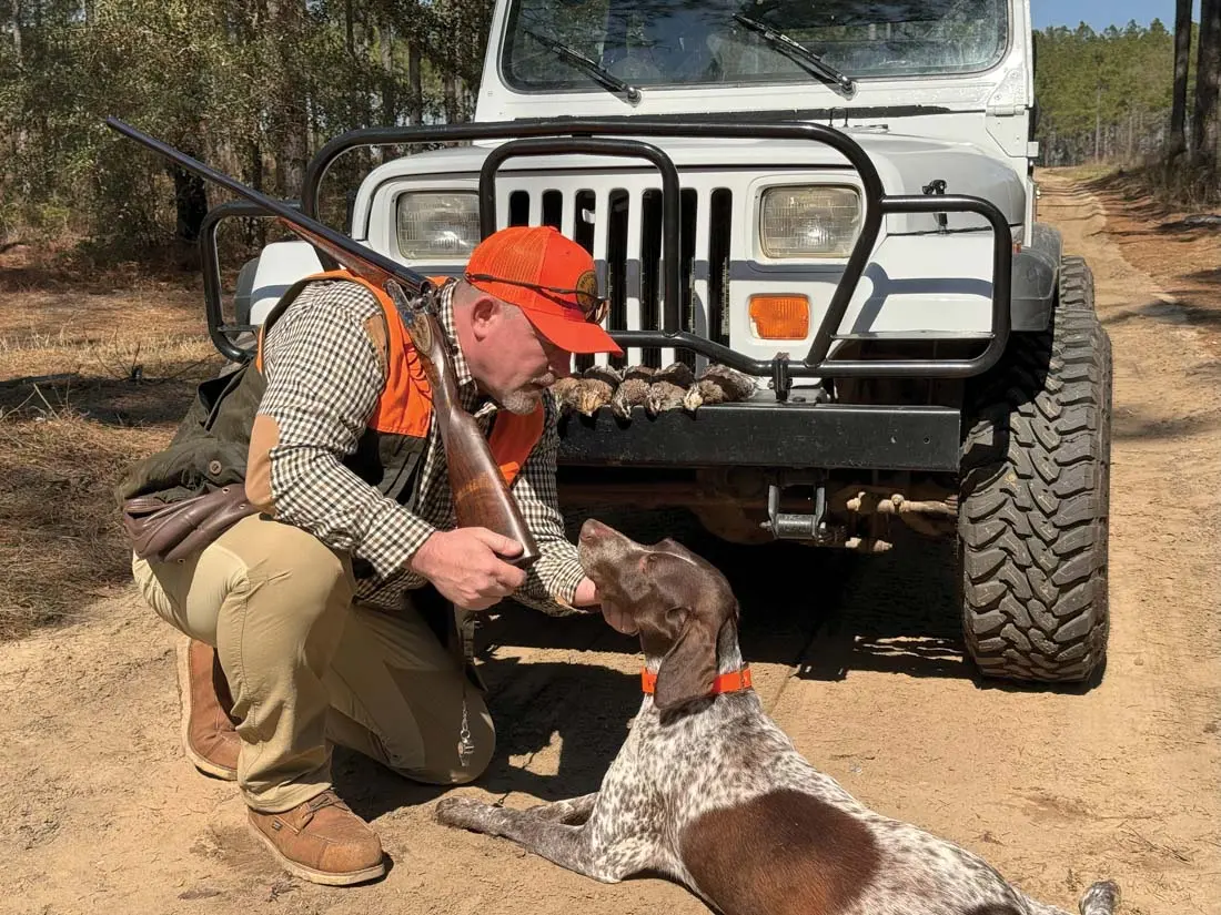 man with hunting dog in front of a jeep