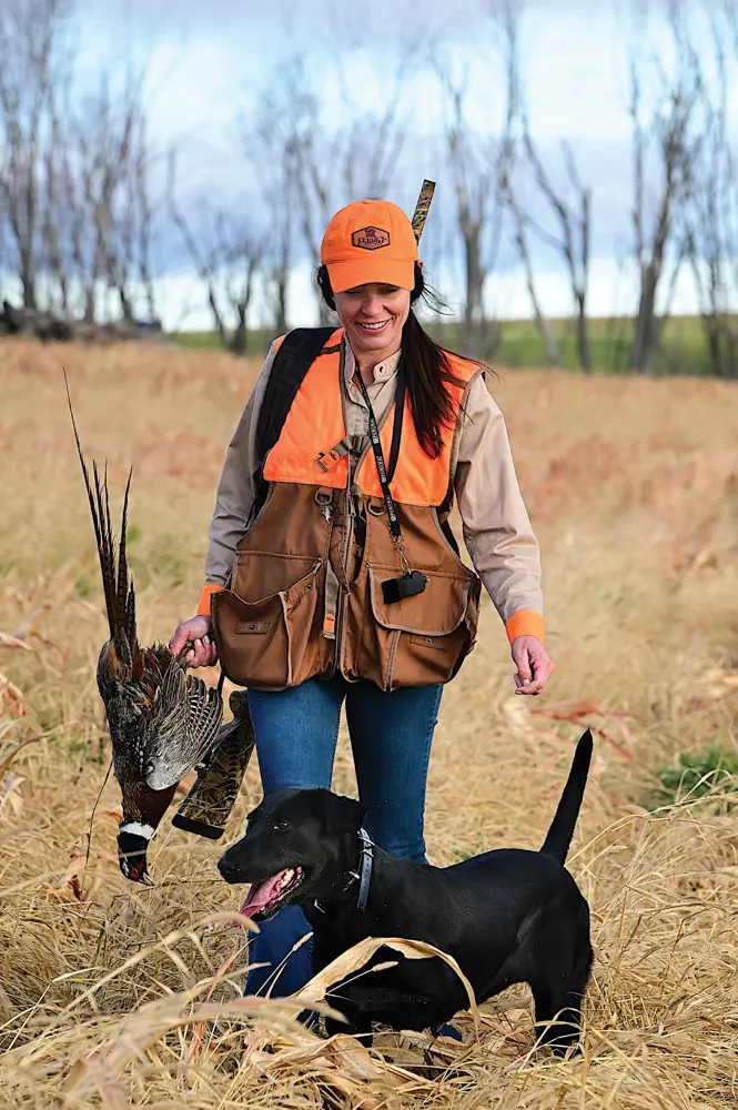 Lady pheasant hunter with black lab