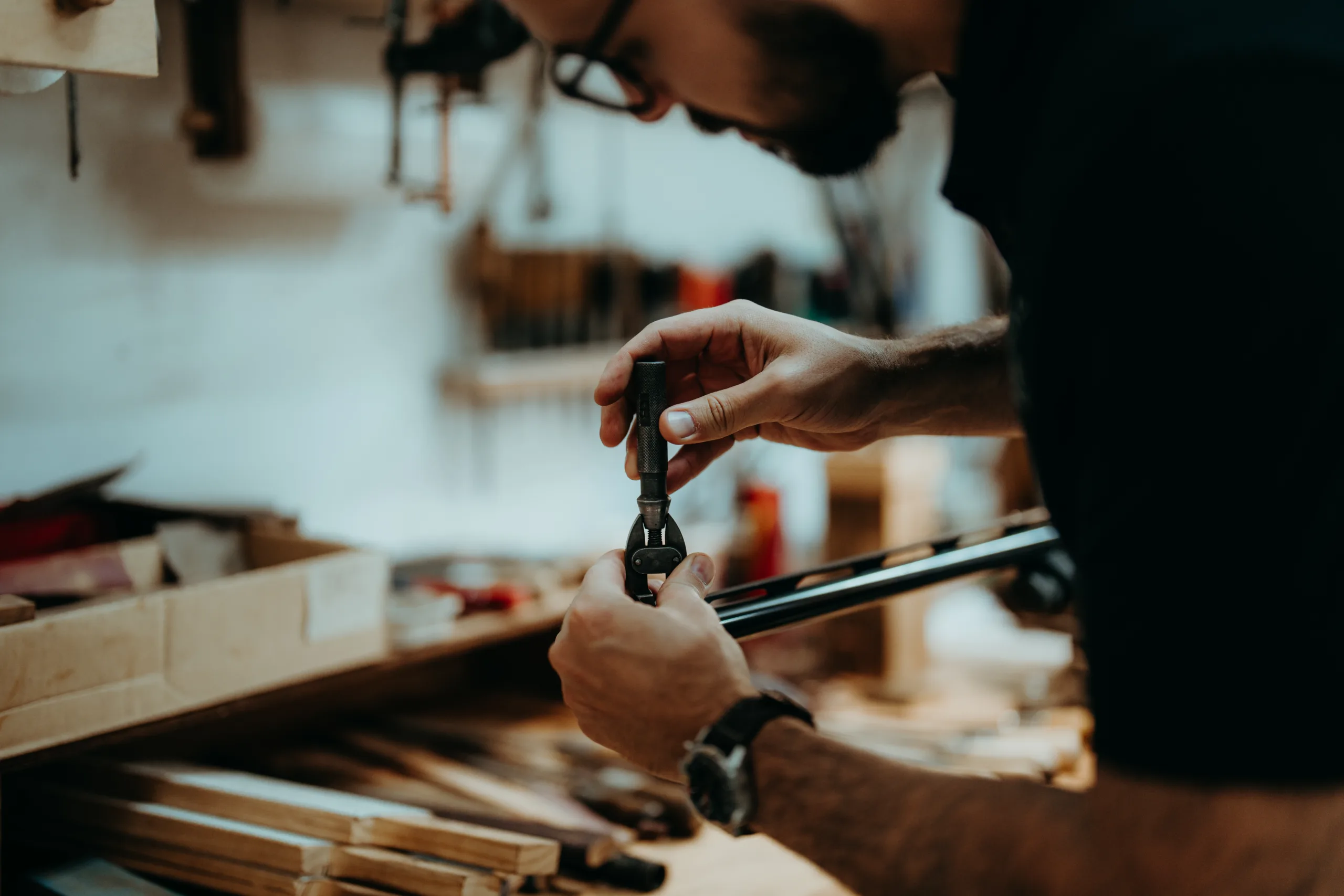 A gunsmith works on the barrel of a shotgun.